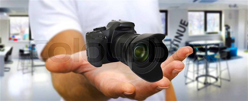 Young man holding modern digital camera in his hand, stock photo