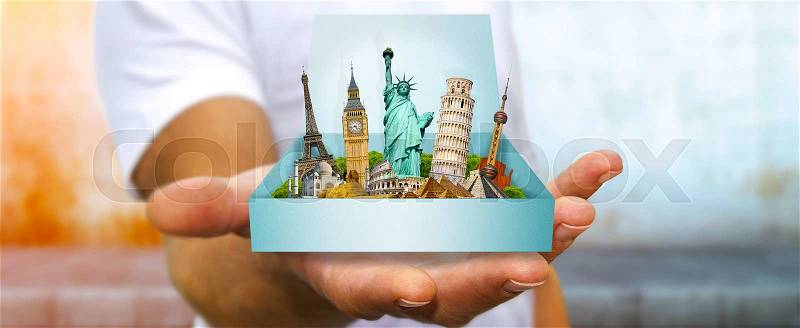 Young man holding travel box in his hand containing famous monuments of the world, stock photo