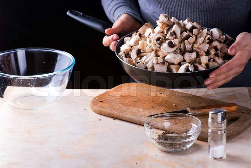 Female hands hold fresh mushrooms in the pan, stock photo