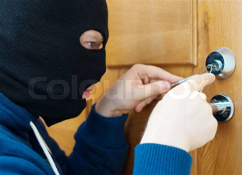Thief opening door with lock picker, stock photo