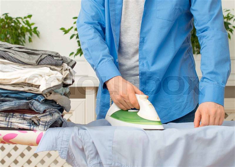 Man ironing clothes on ironing board at home, stock photo