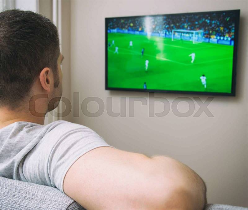 Man watching football match on television at home, stock photo