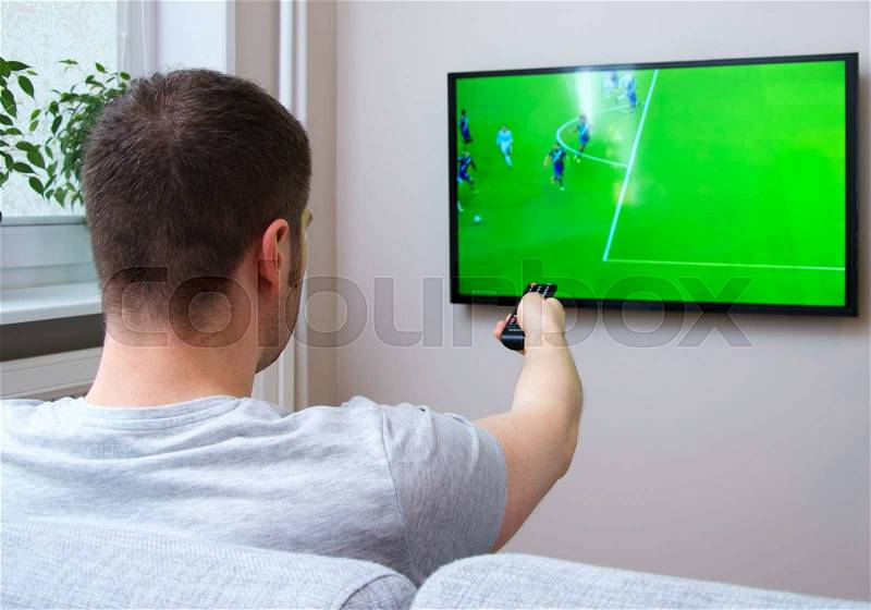 Man watching football match on television at home, stock photo