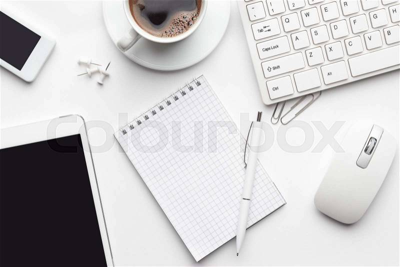 Overhead of white office table with notebook, computer keyboard and mouse, tablet pc and smartphone, stock photo
