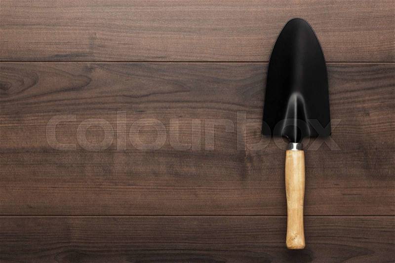 Black gardening shovel on the wooden table with copy space, stock photo