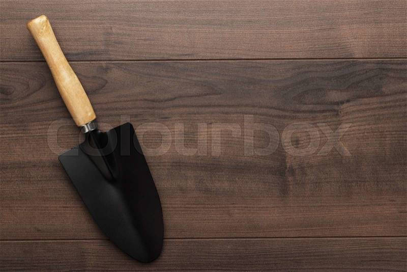 Black gardening shovel on the wooden table with copy space, stock photo