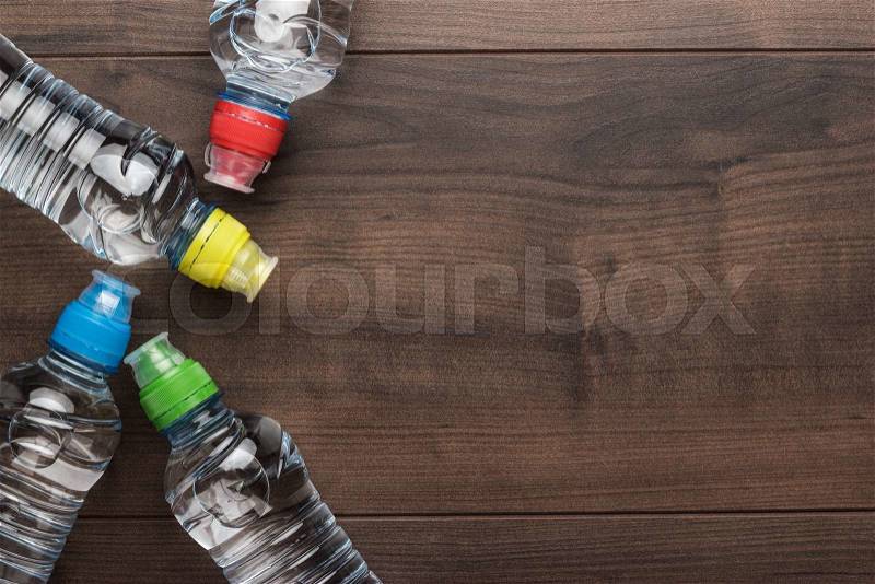 Plastic water bottles with caps of different colour on the wooden table, stock photo