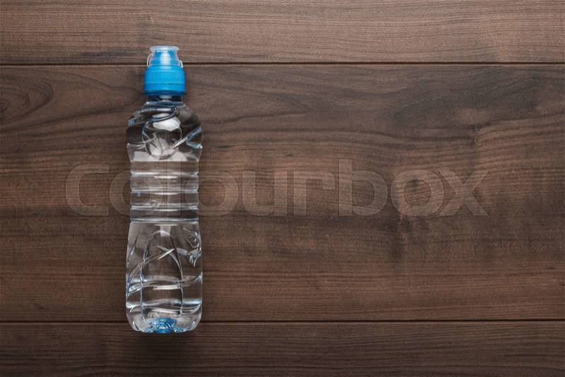 Plastic water bottle with blue cap on the wooden table, stock photo