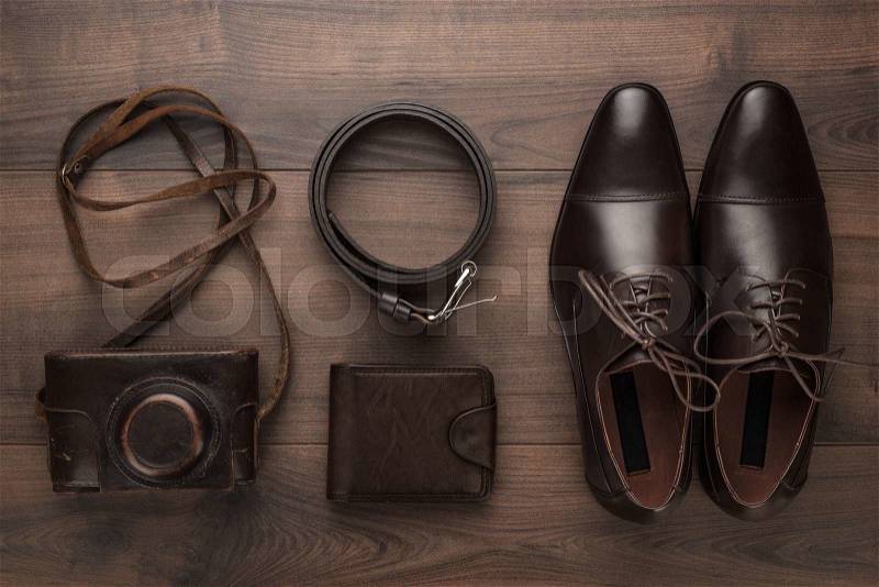Brown shoes, purse, belt, and film camera on wooden table, stock photo