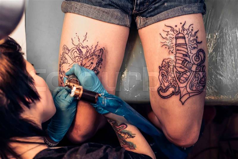 Top view of making tattoo on legs in salon. Showing processing of making a tattoo by woman artist. Tattooist machine,gun. Free space to fill,text, stock photo