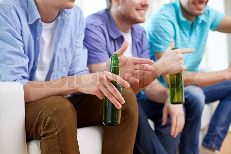 Friendship, leisure, people and alcohol concept - close up of happy male friends drinking beer and watching tv at home, stock photo