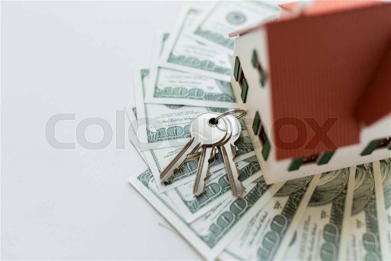 Mortgage, investment, real estate and property concept - close up of home model, dollar money and house keys, stock photo