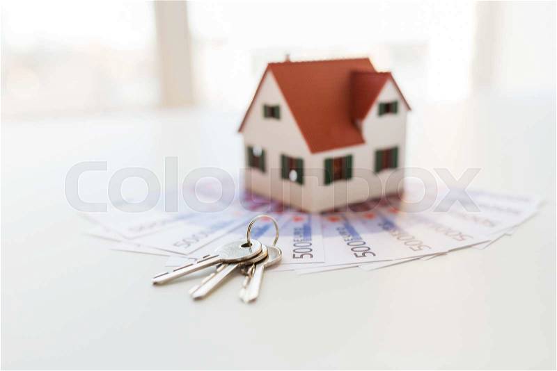 Mortgage, investment, real estate and property concept - close up of home model, money and house keys, stock photo
