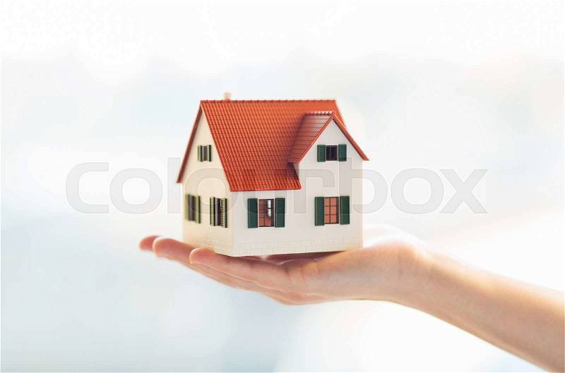 Architecture, building, construction, real estate and property concept - close up of hands holding house or home model, stock photo
