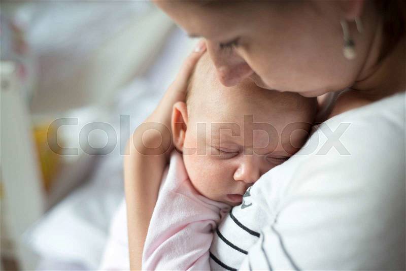 Close up of young mother holding her cute baby daughter, kissing her, stock photo
