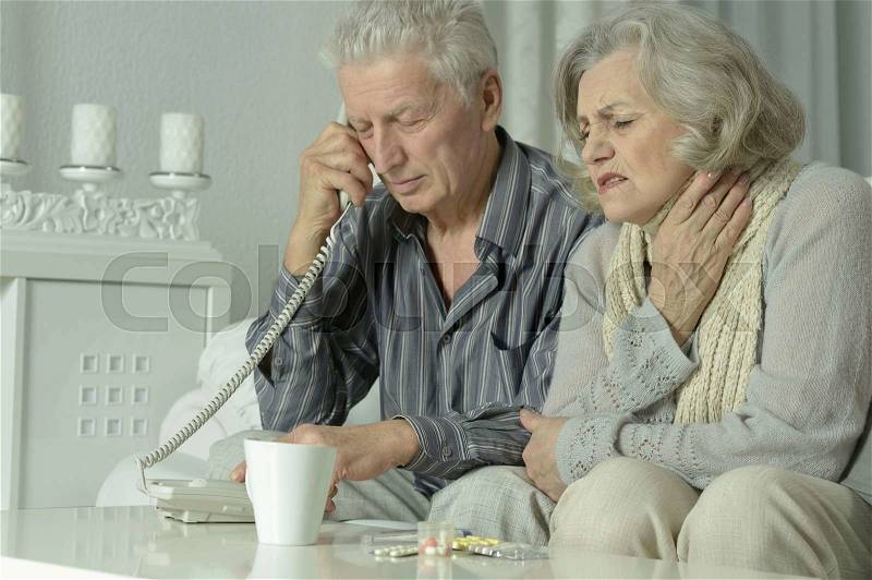 Portrait of sick elderly couple with phone, stock photo