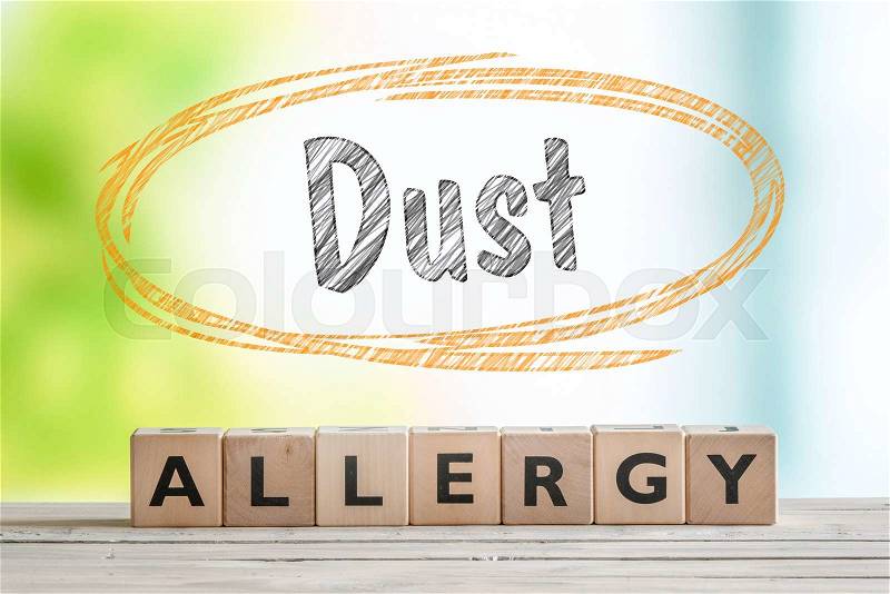 Dust allergy headline on a wooden table with a nature background, stock photo