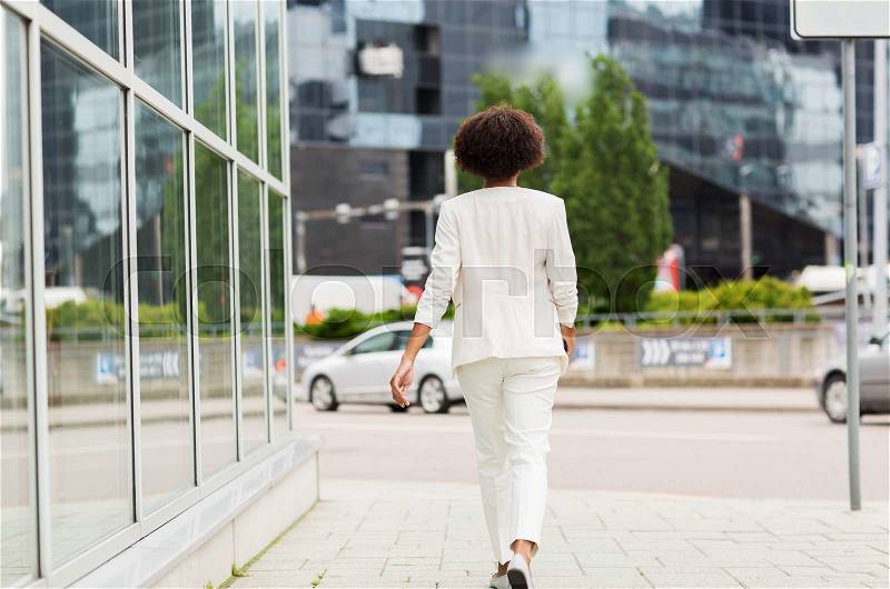 Business and people concept - young african american businesswoman walking in city, stock photo