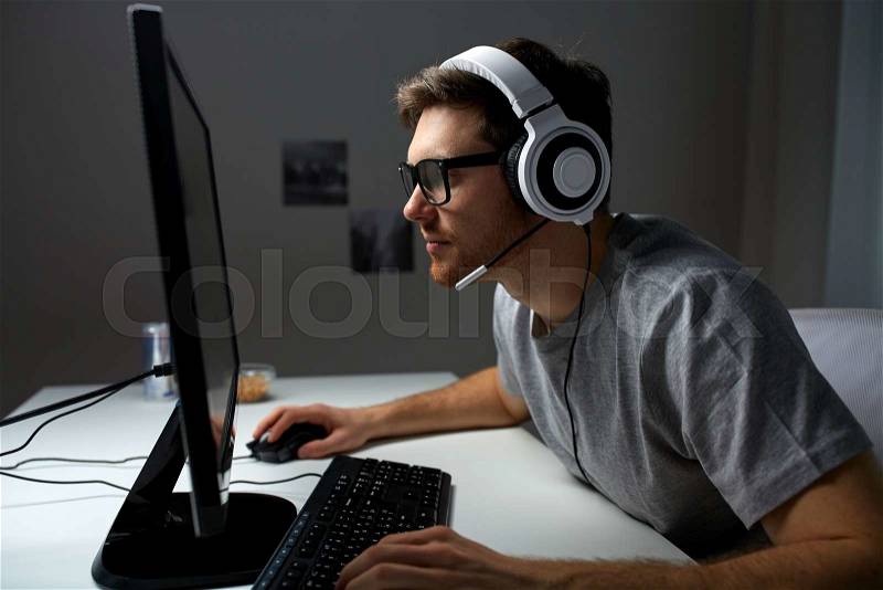 Technology, gaming, entertainment, let\'s play and people concept - young man in headset and glasses with pc computer playing game at home and streaming playthrough or walkthrough video, stock photo
