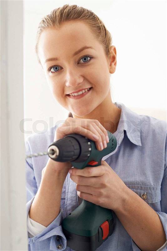 Young Woman Using Electric Drill In House Renovation Project, stock photo