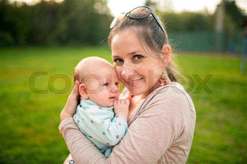 Mother holding her cute baby daughter, outside in spring nature, stock photo