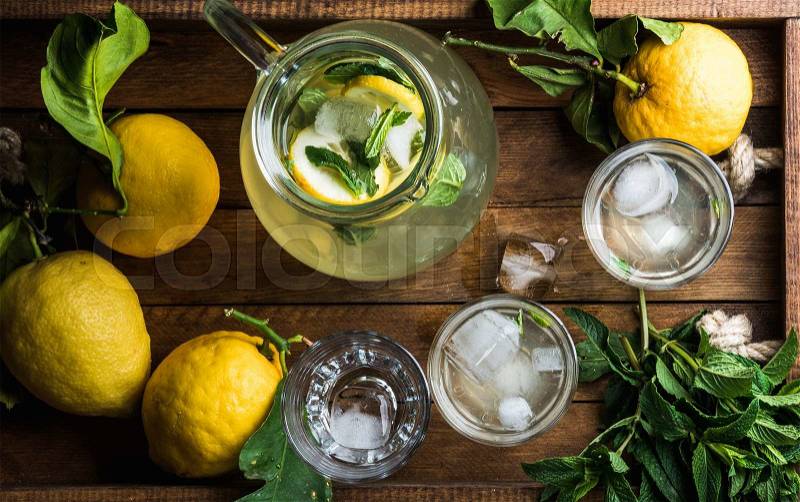 Homemade lemonade with mint and ice, served with fresh lemons over wooden background, top view , stock photo