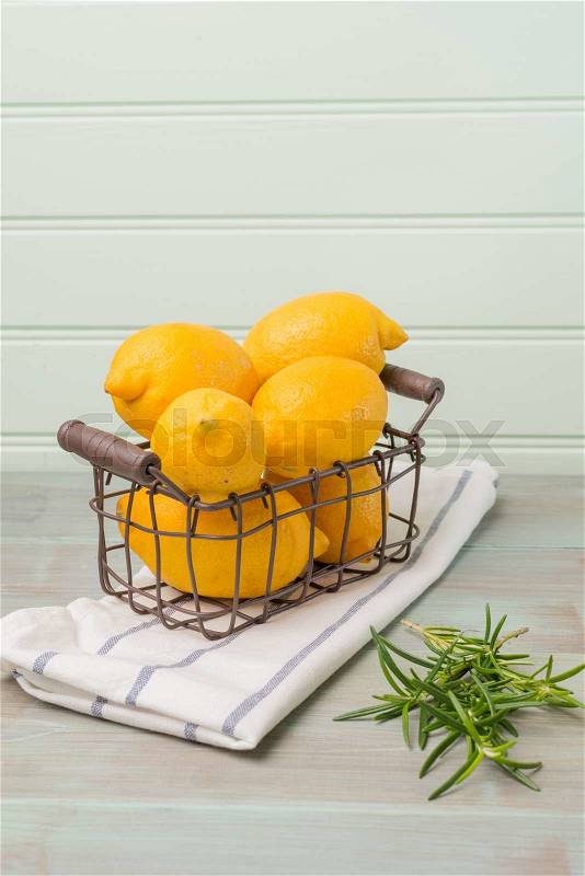 Lemons in a old wire basket on a wooden green background, stock photo