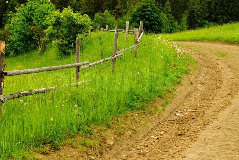 Rural landscape with road and wooden fence, stock photo