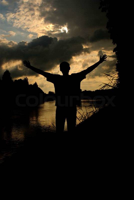 Silhouette man arms raised sunset sky landscape, stock photo
