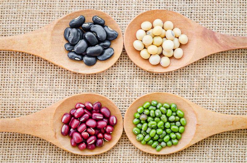 Mix from different beans, black bean, soy bean, azuki bean, mung bean in wooden spoon on the sackcloth background, stock photo
