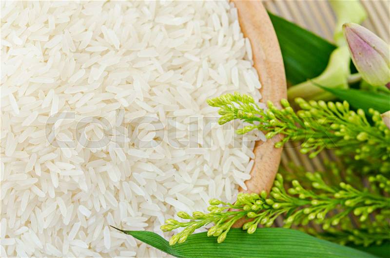 Raw white rice in a bowl with flower - top view, stock photo