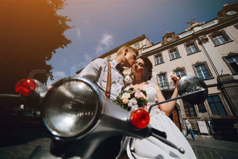 Bride and groom posing on a vintage motor scooter, stock photo