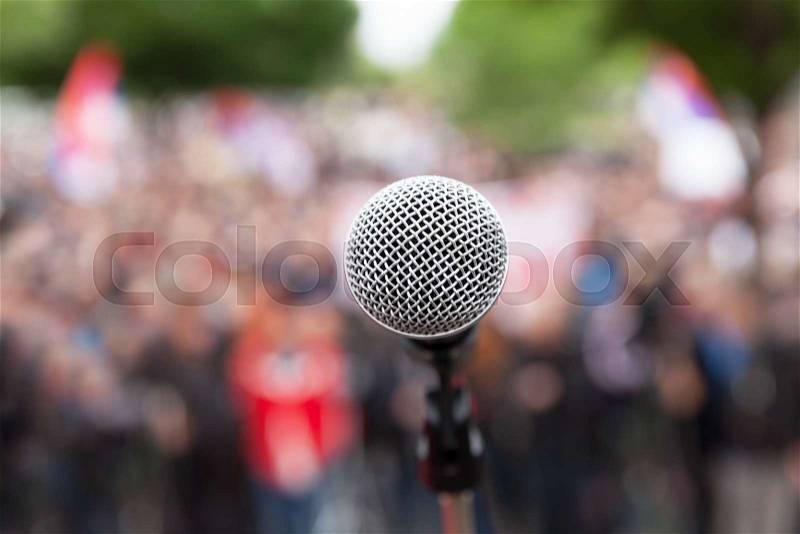 Microphone in focus against blurred audience. Political rally, stock photo