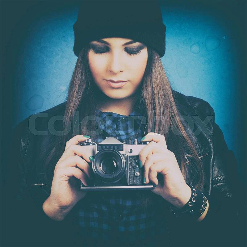 Beautiful young woman holding camera on blue background, stock photo