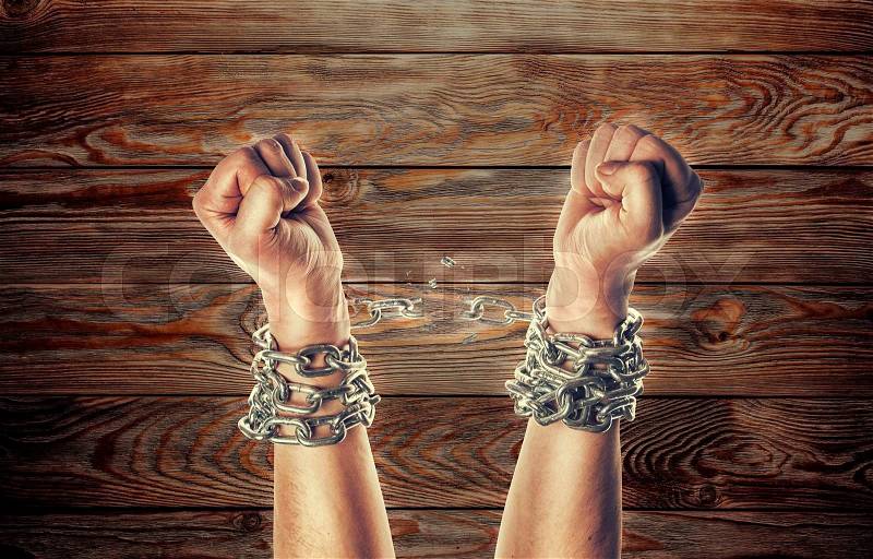 Two hands in chains on a wooden background background with scratches, stock photo