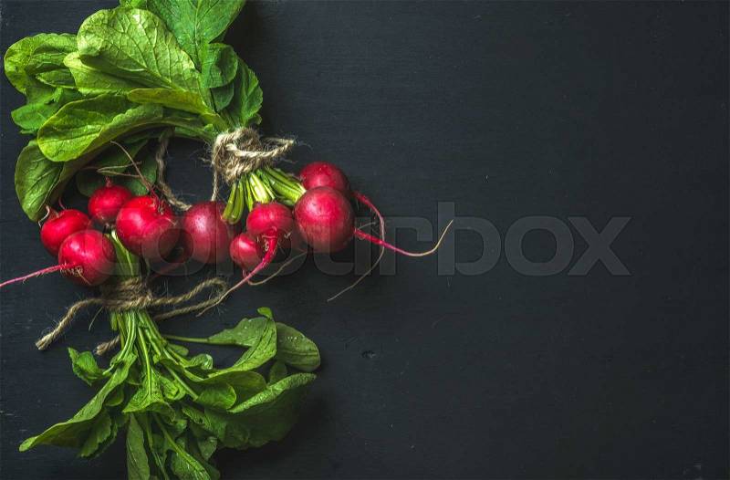 Bunch of radish with leaves on black background, top view, copy space, stock photo
