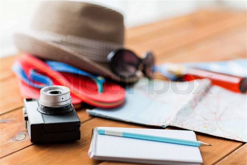 Summer vacation, travel, tourism and objects concept - close up of camera, notepad with pencil and personal accessories, stock photo