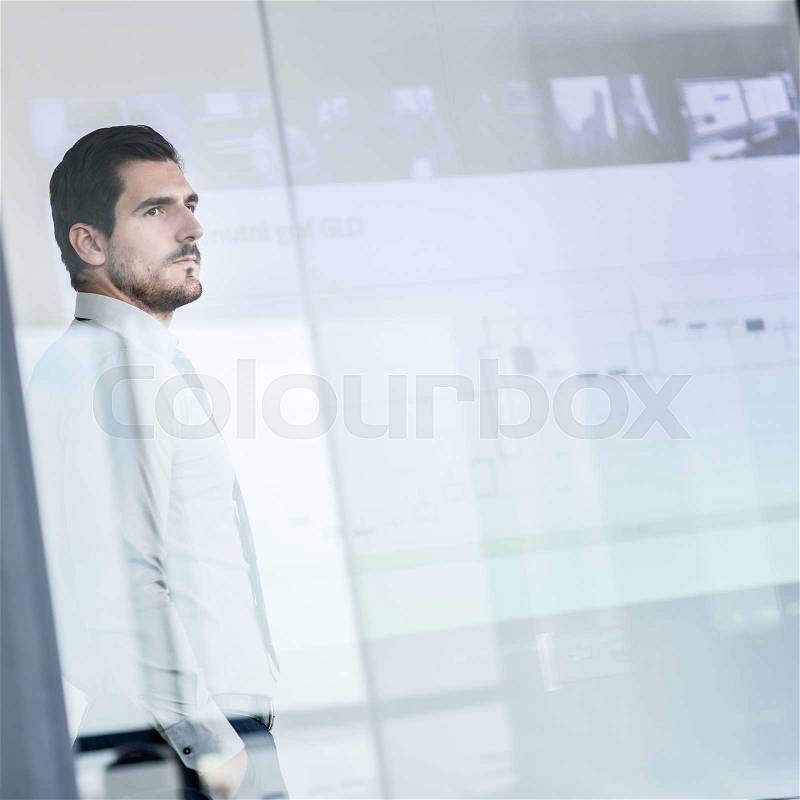 Business man making a presentation in front of whiteboard. Business executive delivering a presentation to his colleagues during meeting or in-house business training. View through glass, stock photo