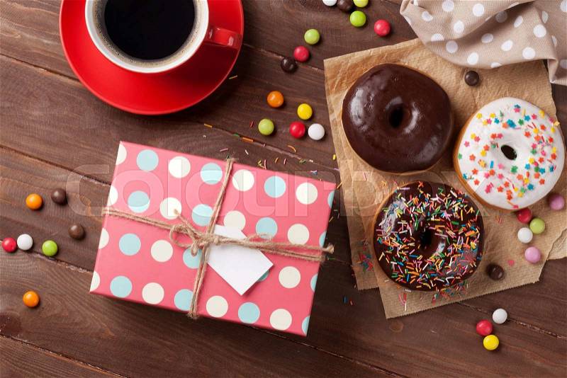 Donuts, gift box and coffee on wooden table. Top view, stock photo