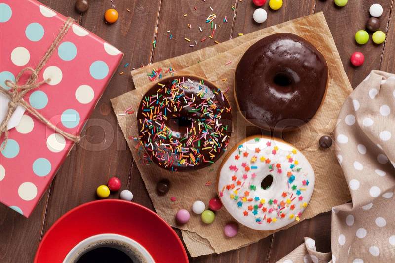 Donuts, gift box and coffee on wooden table. Top view, stock photo