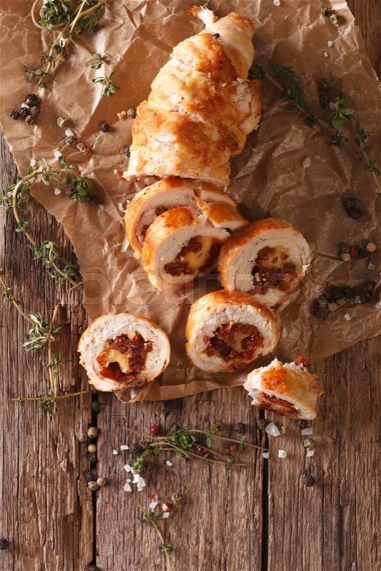 Chicken roll stuffed with cheese and sun-dried tomatoes close-up on the table. vertical view from above\, stock photo