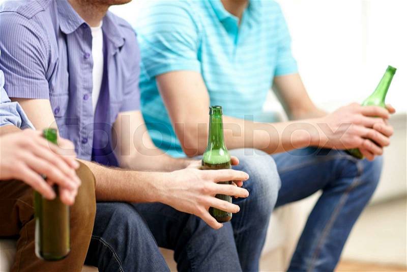 Friendship, leisure, people and alcohol concept - close up of happy male friends drinking beer at home, stock photo