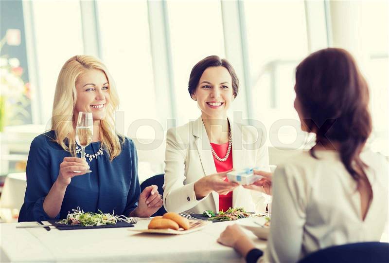 People, holidays, celebration and lifestyle concept - happy women giving birthday present at restaurant, stock photo