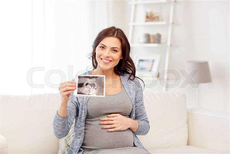 Pregnancy, motherhood, people and medicine concept - happy pregnant woman holding at ultrasound image at home, stock photo