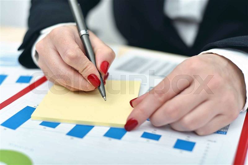 Trader woman taking notes on a sheet of paper, stock photo