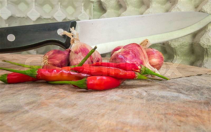 Red peppers, onions on a cutting board with a knife stuck, stock photo