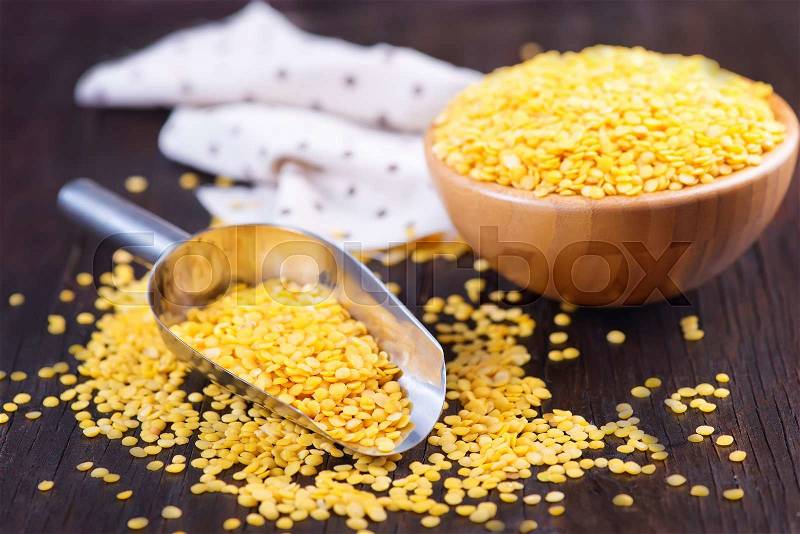 Yellow lentil in bowl and on a table, stock photo