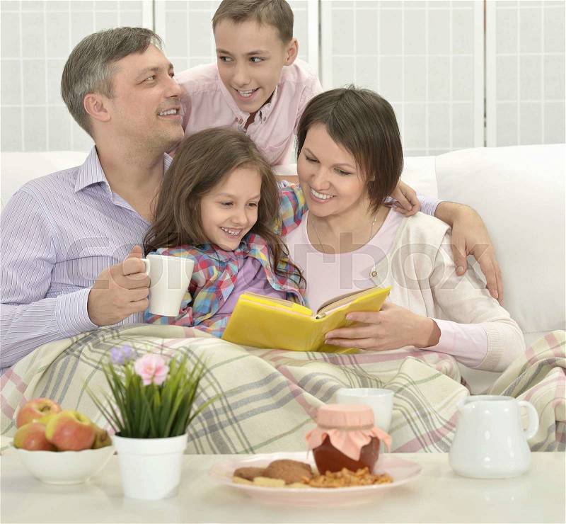 Happy family in a room reading book, stock photo