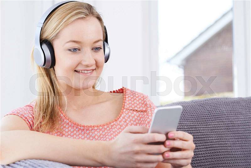 Woman Streams Music From Mobile Phone To Wireless Headphones, stock photo