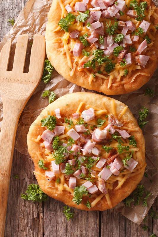 Hungarian pancakes langos with ham and cheese close-up on the table. Vertical view from above\, stock photo